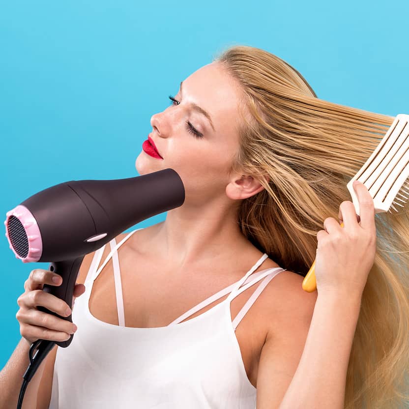 a nice girl holds the hair dryer to blow hair properly